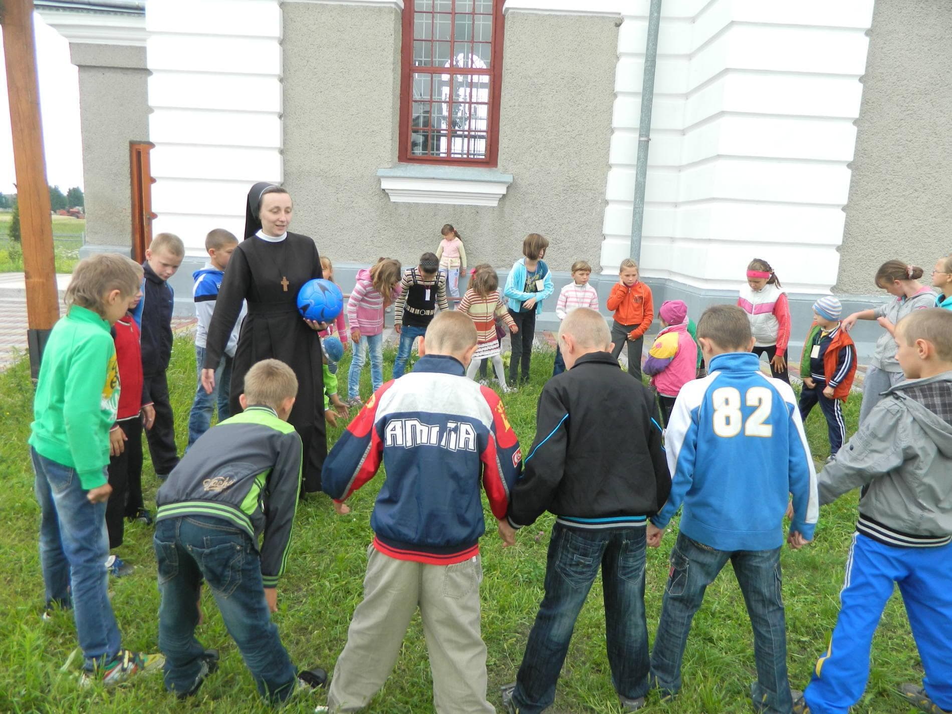Eine Ordensschwester spielt mit Schulkindern (© ACN)